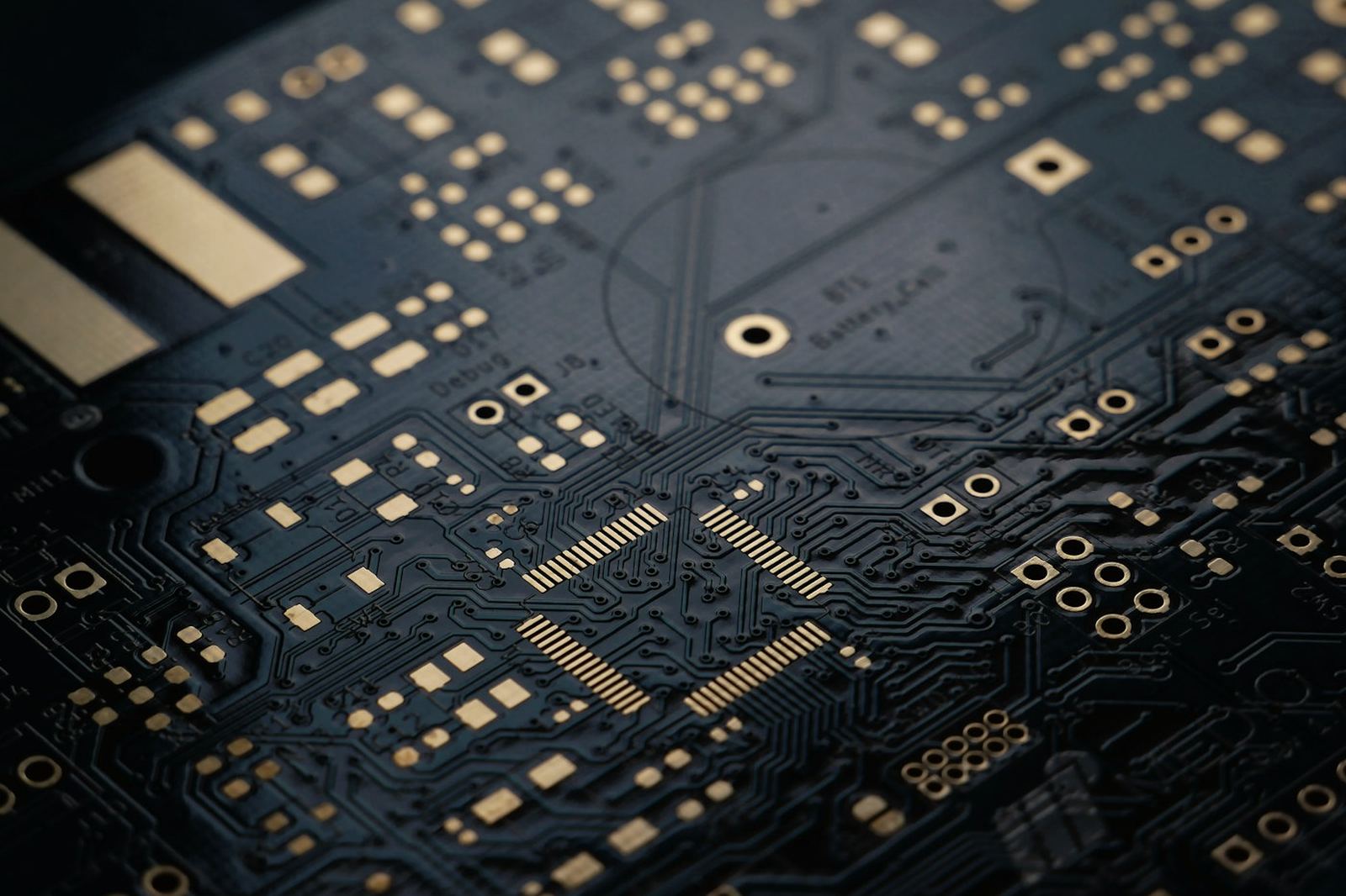 A close view of a dark circuit board with gold contacts.